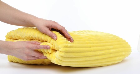 Woman with folded yellow blanket on white background, closeup