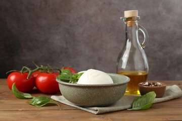 Tasty mozzarella balls, tomatoes, oil and basil on wooden table