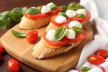 Tasty sandwiches with mozzarella cheese, tomatoes and basil on wooden table, closeup