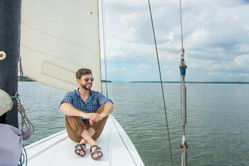 Young man sitting on yacht in sea, copy space.