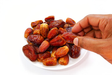 Picking a date fruit with bunch of dates with plate close-up view 
