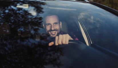 Male driver enjoying a cheerful moment while driving car in nature