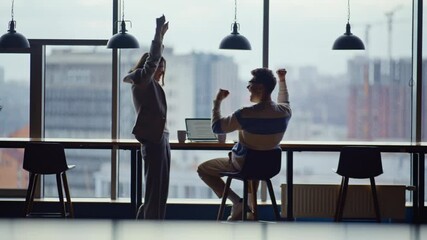 Emotional teammates watching computer celebrating victory in contemporary office - Powered by Adobe