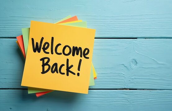 Welcome back written on yellow paper. Text words typography, business, school, life motivation. Inspirational banner. Back to school concept on wooden blue background.