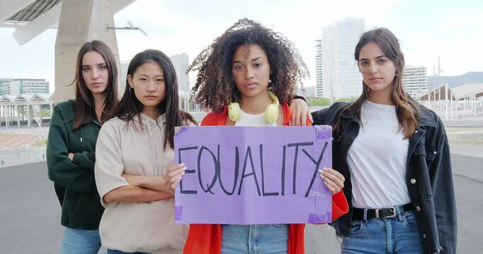 Young Women Looking Seriously at Camera Holding Feminist Sign Saying Equality