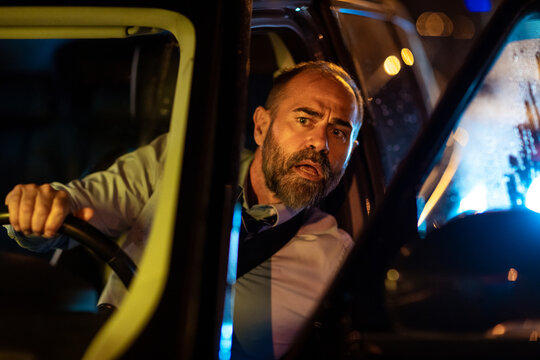 Middle aged caucasian businessman peeking out of his car to check what is causing the traffic in the evening