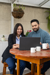 A young woman and a man stand side by side, looking at a laptop screen and discussing data. The office environment reflects teamwork, communication, and professional collaboration.

