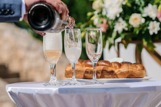 Elegant Wedding Champagne Pouring Ceremony with Challah Bread on White Table with Floral Decor