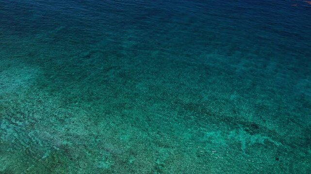 Toma a&eacute;rea de drone haciendo un zoom out desde el mar azul y cristalino, revelando la costa, la zona hotelera y la playa en Canc&uacute;n M&eacute;xico.