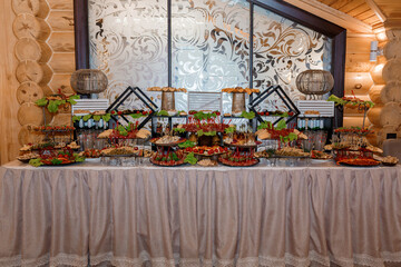 Rustic Wooden Interior Catering Table Display with Appetizers, Elegant Decor, Ornate Glass Panel, and Warm Lighting Ambience