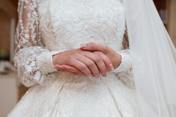 Elegant bride in lace wedding dress with veil, hands clasped, beautiful detail, pearl nails, ivory...