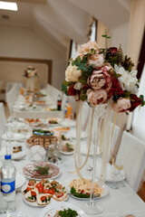 Elegant Wedding Table Setting with Floral Centerpiece: Luxurious Reception, Champagne, White Linens and Burgundy Accents.