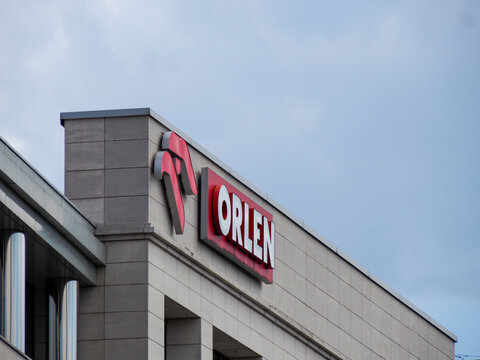 Modern commercial Orlen building exterior with distinctive red corporate branding against cloudy sky in business district