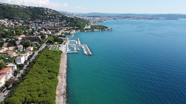 A stunning drone view of Trieste from Barcola, showcasing the city's coastline, historic buildings, and Adriatic charm under a clear northern Italian sky.