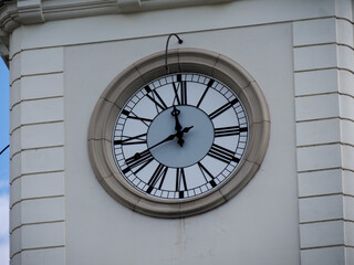 Classical building clock tower showing Roman numerals on white stone facade with architectural geometric patterns