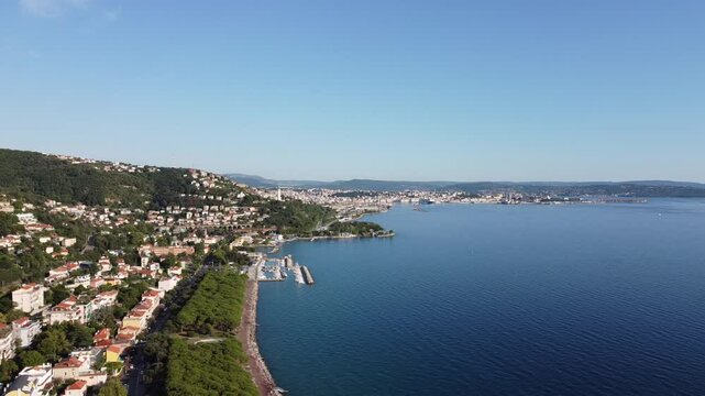 A stunning drone view of Trieste from Barcola, showcasing the city's coastline, historic buildings, and Adriatic charm under a clear northern Italian sky.
