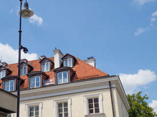 Traditional European residential building with red tile roof against bright blue summer sky