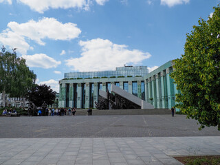 Modern glass and concrete architectural building complex viewed from pedestrian plaza with trees