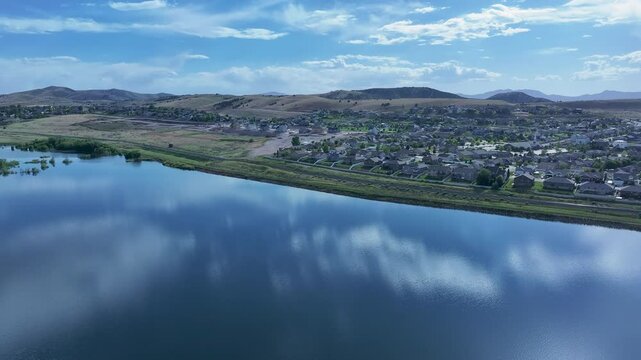 Aerial residential neighborhoods lake Utah mountain valley 1 4K. Orchard, farms and rural ranch property. Lake used for irrigation and recreation. Rural landscape in mountain valley. Agricultural. 
