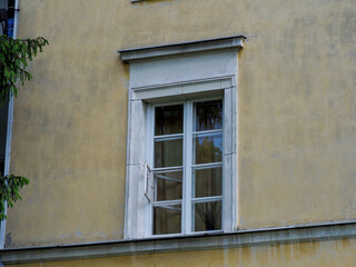 Classic European building window with white wooden frame and glass panes reflecting natural light