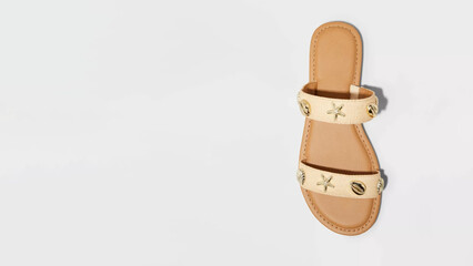 Stylish tan slide sandal with decorative embellishments displayed on a white background