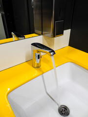 Modern chrome faucet with bright yellow accent wall in contemporary bathroom interior design