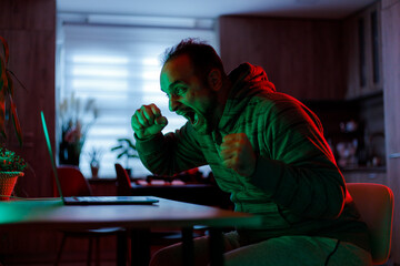 Excited man celebrating victory while gaming at home in the evening