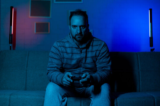 Man playing video games in a modern living room with colorful lights