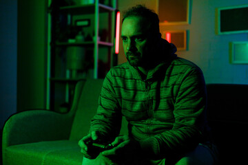 Man playing video games in a dimly lit room with neon lights