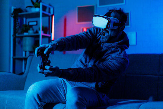 Man enjoys virtual reality gaming in a colorful room at night