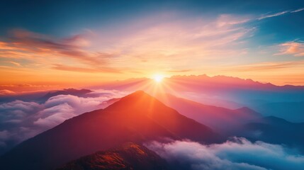 Majestic mountain sunrise casting vibrant light over serene clouded landscape