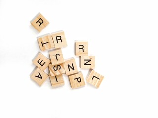 Scattered wooden letter tiles from a word board game on white background, representing education, communication, creativity, language learning, and literacy in a minimal flwooden blocks with word help