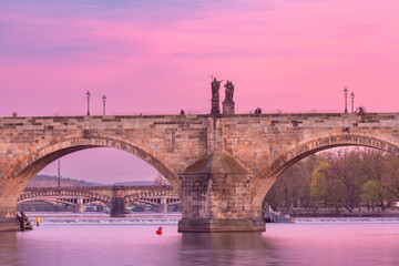Stone arches and statues of Charles Bridge at sunrise in Prague, Czech Republic