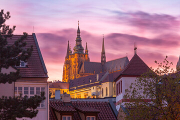 View of St Vitus Cathedral above rooftops at sunset in Prague, Czech Republic