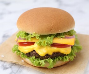 Tasty cheeseburger on white marble table, closeup