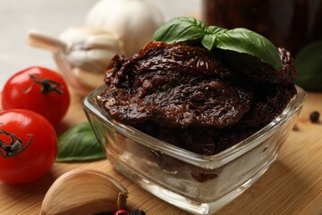 Delicious sun dried tomatoes, fresh vegetables, basil and garlic on wooden table, closeup