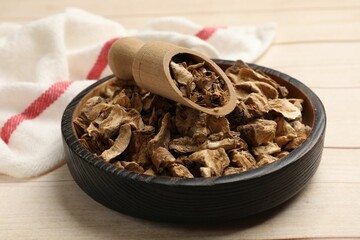 Pieces of dry chicory roots in bowl and scoop on wooden table, closeup