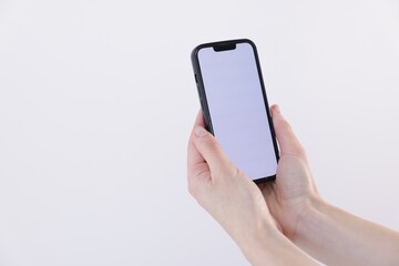 Woman holding smartphone with blank screen on white background, closeup. Mockup for design
