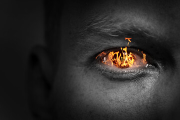Man with fire burning in his eye, closeup. Black and white effect