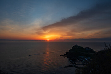 朝焼けの朝 対岸の山並みから昇る朝日 光る海