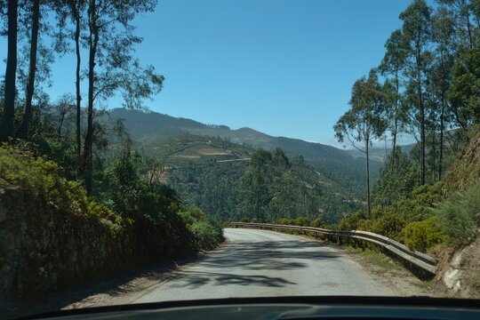 Winding road through a lush mountain valley.  View from car