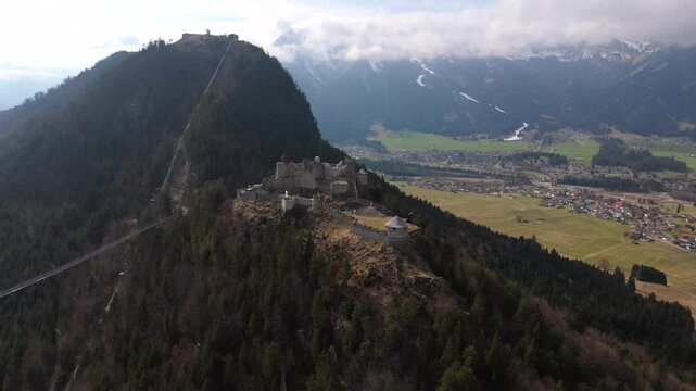 Ehrenberg Castle medieval fortress near Reutte, Austria, overlooks alpine landscape of Lechtal Alps. Famous highline179 suspension bridge stretches across the valley, linking historic fortifications. 