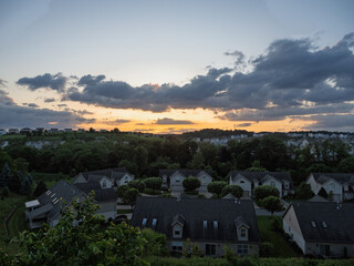 Colorful, orange sunset with clouds and sky over a summer residential neighborhood in USA.