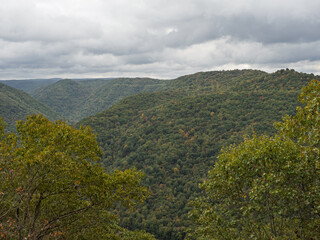 Early fall-colored tree-covered mountains at New River Gorge National Park, West Virginia, beneath a sky filled with clouds.