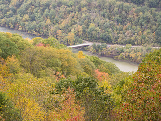 The mountains at New River Gorge National Park, with foliage in early fall colors, with bridges crossing the river.