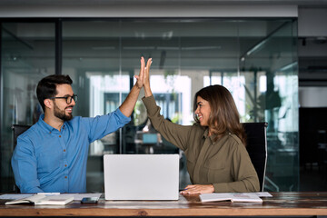 Plakat Happy successful business team of two executive partners employees giving high five supporting celebrating professional success growth financial work achievement sitting at office meeting with laptop.