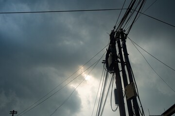 A striking perspective of a utility pole with tangled electrical wires stretching across a dramatic...