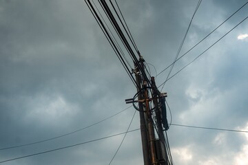 A striking perspective of a utility pole with tangled electrical wires stretching across a dramatic...