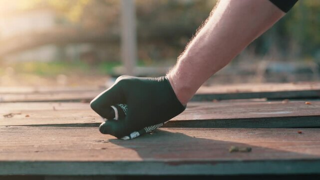 Volunteer hand in black latex glove crushing and picking up paper coffee cup from picnic table slow motion environmental cleanup with frustration