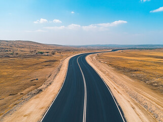 Empty asphalt road stretching through a vast desert landscape under a sunny sky